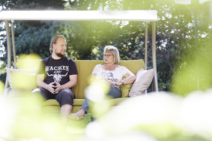 Ein junger Mann und eine Frau sitzen auf einer Hollywood-Schaukel und unterhalten sich