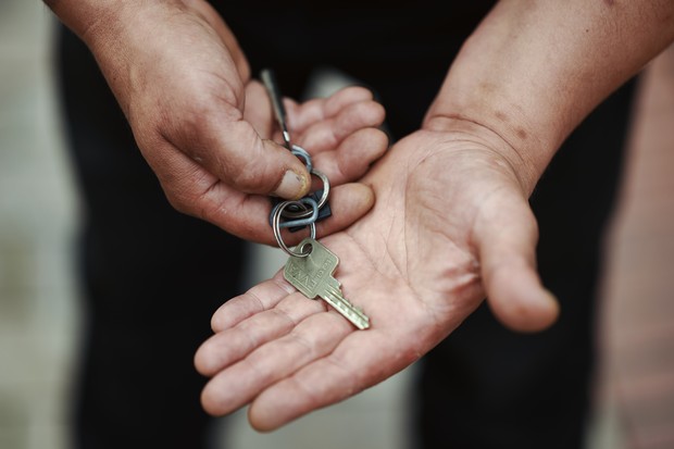 Ein Mann hält einen Haustürschlüssel in der Hand Ein Mann hält einen Haustürschlüssel in der Hand